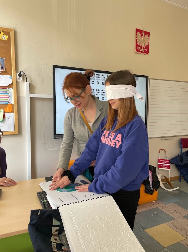 Instructor showing a tactile book to a blindfolded student