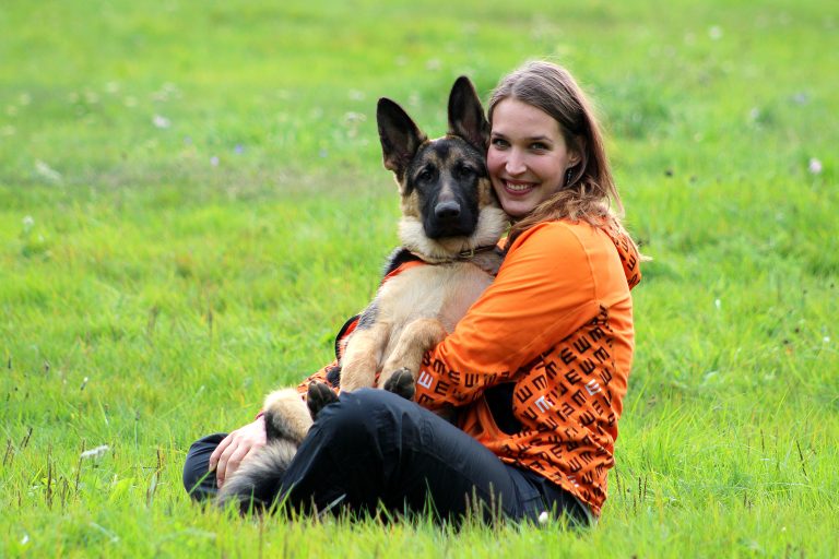 Linda sitting on the grass with a german shepherd